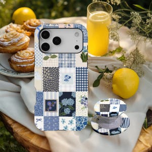 Puede incluir: Una funda para smartphone y un soporte circular para teléfono a juego con un diseño de patchwork en azul y blanco. El patrón consta de varios cuadrados con motivos florales, cuadros vichy, rayas y texturas azul marino sobre un fondo claro.
