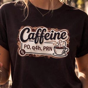 May include: A white ceramic mug with a black handle and the text "But First, Coffee" in a black, handwritten-style font. The mug is on a white surface.