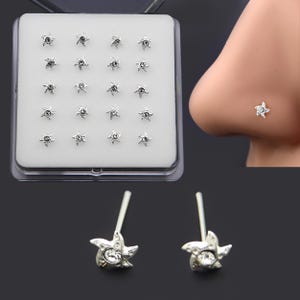 May include: A set of silver-colored nose studs in a clear plastic case. Each stud is shaped like a starfish with a small, clear gem in the center. One stud is shown in a person's nose.
