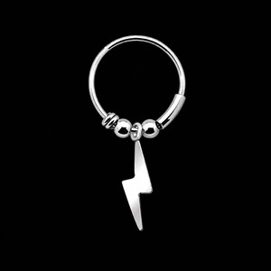 May include: A silver hoop earring with a lightning bolt charm. The earring features a circular design with small beads and a polished lightning bolt pendant. The jewelry is set against a black background.