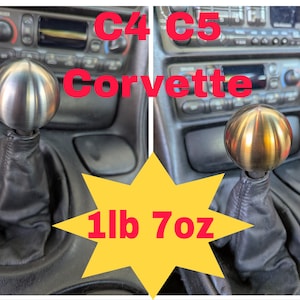 May include: A pair of Corvette C4 and C5 shift knobs. The C4 knob is silver, and the C5 knob is gold. The text "Corvette" is in red. The weight is 1lb 7oz.