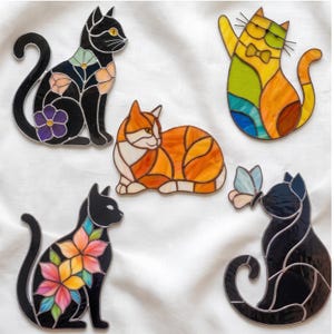 Peut inclure: Cinq décorations en vitrail représentant des chats. Un chat noir à motifs floraux, un chat orange et blanc, un chat multicolore avec un nœud papillon, un chat noir aux fleurs roses et jaunes, et un chat noir avec un papillon bleu clair.