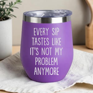 May include: A purple insulated wine tumbler with a silver rim and clear lid. The tumbler has the phrase "EVERY SIP TASTES LIKE IT'S NOT MY PROBLEM ANYMORE" printed in white. The tumbler is on a white cloth.
