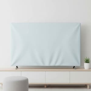 May include: A pale blue TV cover draped over a television set. The cover has a soft, slightly wrinkled texture. The TV is on a white cabinet with a light wood top. A small potted plant sits to the right.