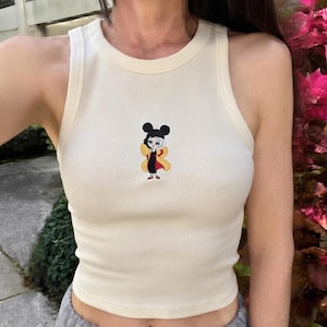 Pode incluir: Uma caneca de cerâmica branca com uma alça preta e o texto "But First, Coffee" em preto, em negrito. A caneca está sobre uma superfície branca. A caneca tem aproximadamente 10 cm de altura.