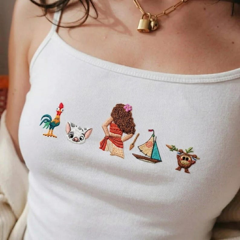May include: A white tank top featuring a series of small, colorful embroidered designs across the chest, including a rooster, a pig face, a person with long brown hair, a small sailboat, and a brown creature holding a wooden staff.