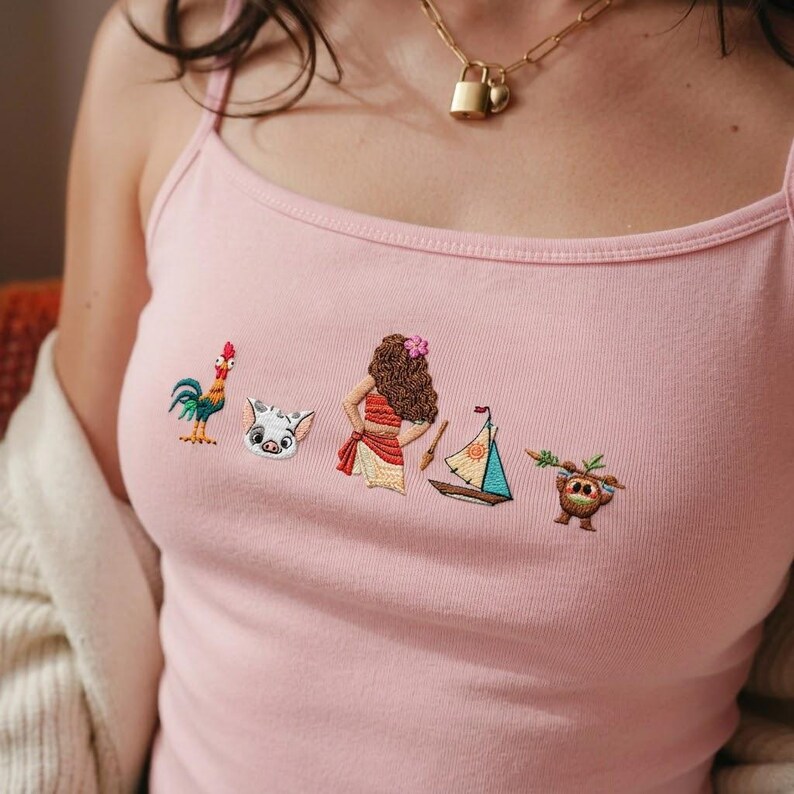 May include: A light pink spaghetti strap tank top featuring a horizontal row of small, colorful embroidered designs including a rooster, a pig face, a female figure with long brown hair, a small sailboat, and a brown creature holding a green branch.
