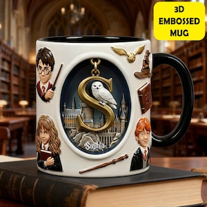 May include: A white 3D embossed mug with a black handle, featuring embossed images of characters, a golden owl, and a castle. The mug has the text "3D EMBOSSED MUG" in a yellow box. The mug is sitting on a book.