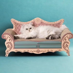 May include: A fluffy white cat lounges on a decorative cat scratcher shaped like a miniature sofa. The cat scratcher has a pink and tan frame with ornate detailing, a blue cushion, and a corrugated scratching surface.