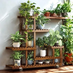 May include: A multi-tiered, wooden plant stand with various potted plants. The stand is made of dark brown wood and has multiple shelves of different sizes. The plants include a variety of green foliage and some with white and patterned pots. The stand has wheels for easy movement.