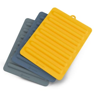 May include: Three silicone trivets in shades of gray, blue, and yellow. Each trivet has a rectangular shape with a series of parallel raised lines. The yellow trivet has a small loop for hanging. The trivets are designed for kitchen use.