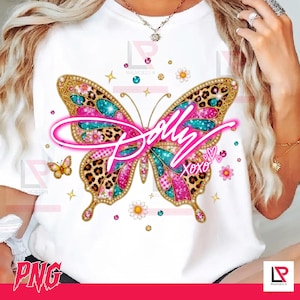 Puede incluir: Una camiseta blanca con un gran gráfico central de mariposa con estampado de leopardo y detalles de purpurina rosa y turquesa. El texto "Dolly" aparece en una fuente cursiva rosa brillante sobre la mariposa, junto a "XOXO" y corazones.