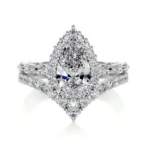 May include: A dazzling engagement ring featuring a pear-shaped diamond center stone surrounded by a halo of smaller diamonds. The ring has a double band, also encrusted with diamonds, creating a sparkling, elegant design.