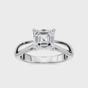 May include: A silver engagement ring with a large, square-cut diamond. The ring features a classic, minimalist design with a smooth, polished band. The diamond is set with four prongs, showcasing its brilliance. A timeless piece of jewelry.