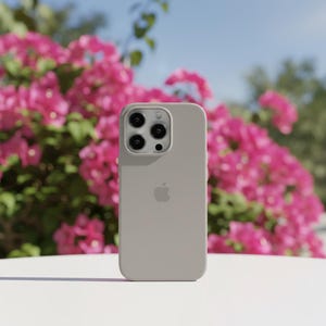 May include: A light gray iPhone case with a triple-lens camera and the Apple logo. The case is made of a smooth material and is set against a backdrop of vibrant pink flowers and a clear blue sky.