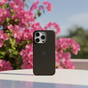 May include: A dark brown smartphone case with a camera module and the Apple logo. The case is shown against a backdrop of pink flowers and a blue sky.