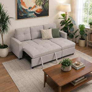 Pode incluir: Um sofá seccional cinza claro com uma chaise longue retrátil. O sofá tem almofadas tufadas e duas almofadas decorativas. Uma mesa de centro de madeira e plantas em vasos estão em primeiro plano. Uma pintura abstrata está pendurada na parede.