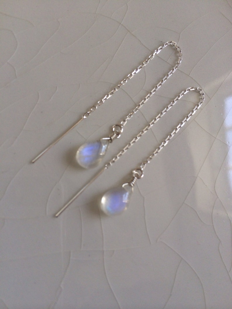 May include: A pair of silver chain earrings with teardrop-shaped moonstone pendants.