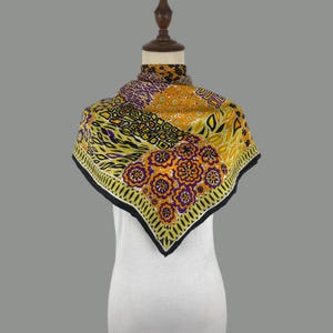 Puede incluir: Un pañuelo cuadrado con un vibrante patrón de mosaico de motivos florales y geométricos en naranja, morado, amarillo y negro. El diseño incluye grupos de flores repetitivas, formas abstractas y un borde negro sólido con un ribete amarillo.