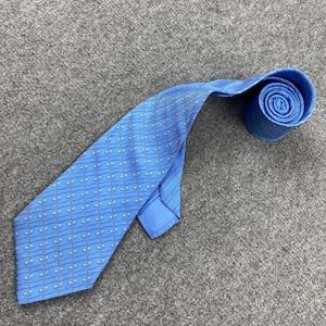 May include: A light blue tie with a repeating pattern of small, stylized figures and diagonal lines. The tie is rolled up at the end, showcasing the fabric's texture and design. The tie is made of a smooth, possibly silk, material.
