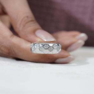 May include: A silver ring with a honeycomb design. Each hexagon is filled with small, sparkling stones. The ring is held by a person with a light skin tone. The brand name "PRASHIV JEWELS" is visible on the ring.