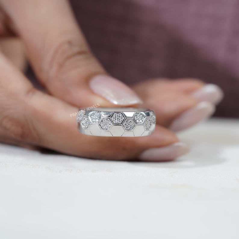 May include: A silver ring with a honeycomb design. Each hexagon is filled with small, sparkling stones. The ring is held by a person with a light skin tone. The brand name "PRASHIV JEWELS" is visible on the ring.