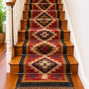 May include: Staircase with wooden steps and a runner rug. The rug features a geometric pattern in red, black, yellow, and beige. Brass rods secure the runner to the steps. The staircase has a white banister and a wooden handrail.