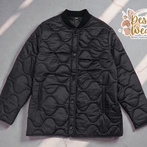 May include: Black quilted jacket with a round collar and button closure. The jacket has a quilted pattern and two front pockets. The Desert Weave logo is in the upper right corner.
