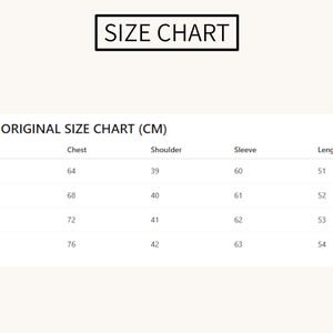 May include: A size chart with the text "SIZE CHART" at the top. The chart displays measurements in centimeters for chest, shoulder, sleeve, and length, with sizes ranging from S to XL. The chart is on a cream-colored background.