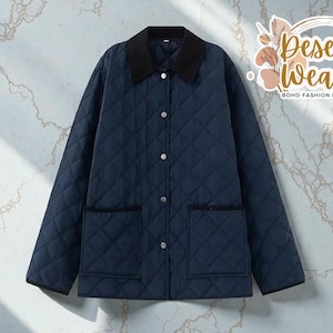 Op de afbeelding: Marineblauwe gewatteerde jas met een zwarte corduroy kraag en twee voorzakken. De jas heeft een ruitpatroon en zilveren knopen. De jas is van de Desert Weave Boho Fashion Boutique.