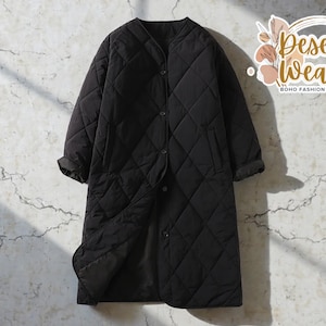 May include: A long, black quilted coat with a button-up front and two pockets. The coat has a diamond pattern and rolled-up sleeves. The coat is from the "Desert Weave Boho Fashion Boutique".