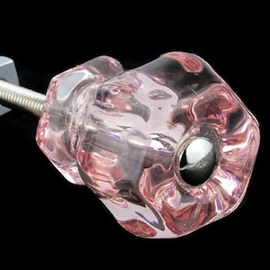 May include: A pink glass cabinet knob with a silver screw and metal base.