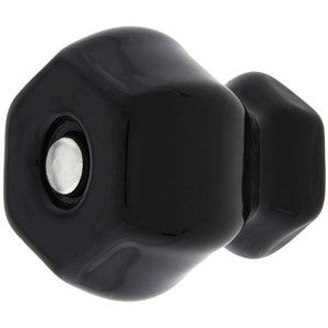 May include: A black ceramic cabinet knob with a hexagonal shape. The knob has a smooth, glossy finish.