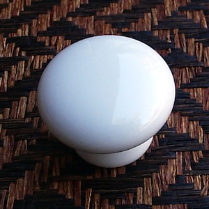 Peut inclure: Bouton de porte en céramique blanche avec une surface lisse et arrondie.