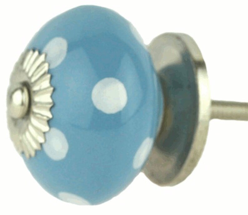 May include: A light blue ceramic knob with white polka dots and a silver metal base. The knob has a decorative silver metal trim around the base.