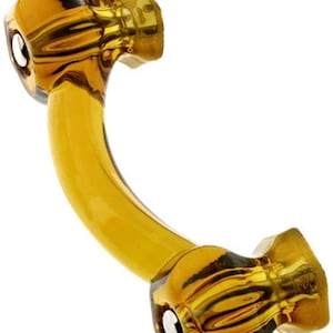 May include: Amber glass cabinet knob with a curved shape and a decorative design. The knob has a silver metal accent on each end.