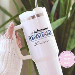May include: White insulated tumbler with a handle, featuring the words "behavior REGISTERED Technician" in black, teal, and blue. The tumbler also includes the name "Lauren" in a script font.