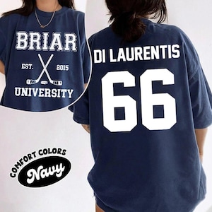 May include: Navy blue t-shirt with white text and graphics. The front features "BRIAR UNIVERSITY" with crossed hockey sticks and "EST. 2015." The back displays "DI LAURENTIS" and the number "66." The shirt is labeled "COMFORT COLORS Navy."