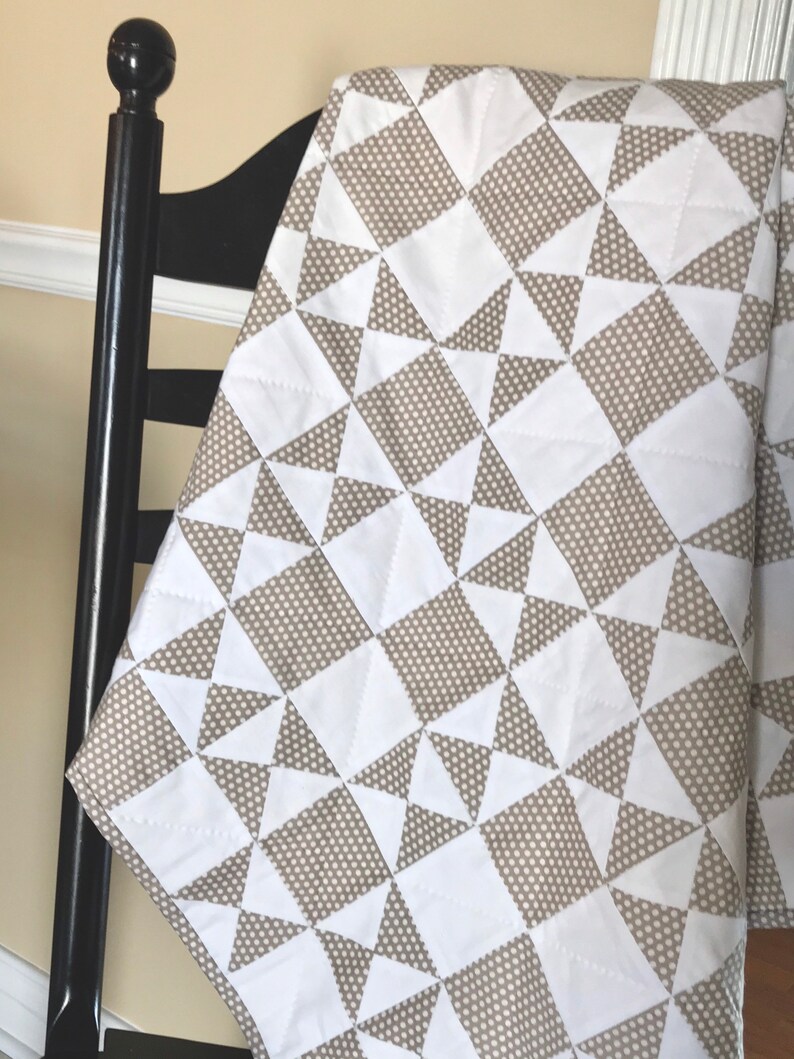 K&ouml;nnte beinhalten: Eine wei&szlig;e und braune Steppdecke mit geometrischem Muster. Die Steppdecke ist aus Baumwollstoff und f&uuml;hlt sich weich und angenehm an.