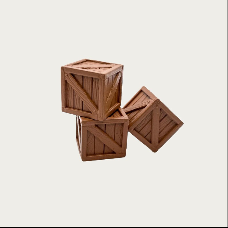 Puede incluir: Tres peque&ntilde;as cajas de madera marr&oacute;n apiladas sobre un fondo blanco. Las cajas tienen un dise&ntilde;o r&uacute;stico con soportes de madera diagonales, creando una est&eacute;tica vintage. Las cajas son de madera.