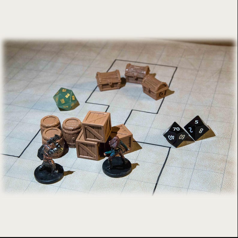 Puede incluir: Una escena de juego de mesa con piezas de juego en miniatura. Hay cajas de madera, barriles y cofres del tesoro. Dos figuras en miniatura est&aacute;n situadas cerca de las cajas. Tambi&eacute;n hay dos dados negros y un dado verde de 20 caras.