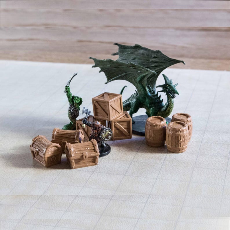 Puede incluir: Una escena de juego de mesa con figuras de fantas&iacute;a en miniatura y terreno. Un drag&oacute;n verde con las alas extendidas se encuentra cerca de barriles y cajas de madera. Otras figuras incluyen un orco verde y un guerrero. Cofres del tesoro marrones est&aacute;n dispersos.