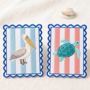 May include: Two rectangular embroidered patches with scalloped blue borders. The left patch features a white and light blue striped background with a pelican. The right patch features a white and coral striped background with a sea turtle.
