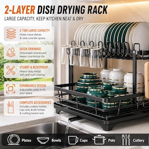 Op de afbeelding: Een zwart afdruiprek met twee niveaus met de tekst "2-LAYER DISH DRYING RACK". Het rek biedt plaats aan borden, kommen, kopjes en bestek. Het bevat een snijplankrek en een bestekhouder. Het rek is ontworpen om de keuken netjes en droog te houden.