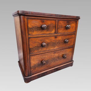 May include: A dark brown wooden chest of drawers with four drawers and round wooden knobs. The chest has a rectangular shape with a slightly curved base and top. The wood grain is visible.