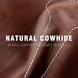 May include: A dark brown cowhide leather surface with a smooth, slightly glossy texture and visible white stitching. The text NATURAL COWHIDE and EVERY LEATHER PRODUCT IS UNIQUE is printed in white across the center of the leather material.