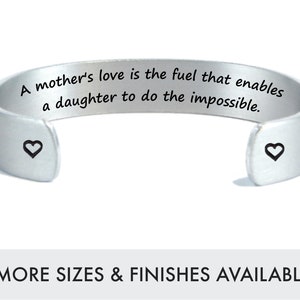 May include: Silver cuff bracelet with the inscription "A mother's love is the fuel that enables a daughter to do the impossible."  Two small hearts are engraved on each side of the bracelet.