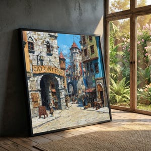 May include: A framed painting depicting a European town square with cobblestone streets, arched entryways, and buildings in shades of beige, blue, and red. The painting includes the text "CIVI CINT CINO" above an archway. The artwork is displayed near a window.