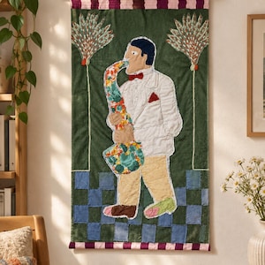 May include: A rectangular fabric wall hanging featuring a quilted applique of a musician playing a floral-patterned saxophone. The figure wears a white jacket, red bow tie, and yellow trousers, standing on a green and blue checkered floor.