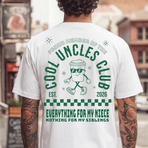 Könnte beinhalten: Weißes T-Shirt mit einem grünen Aufdruck, der "Cool Uncles Club" und eine Cartoon-Kaffeetasse zeigt. Der Text "Everything for my niece, nothing for my siblings" ist ebenfalls auf dem Shirt aufgedruckt.